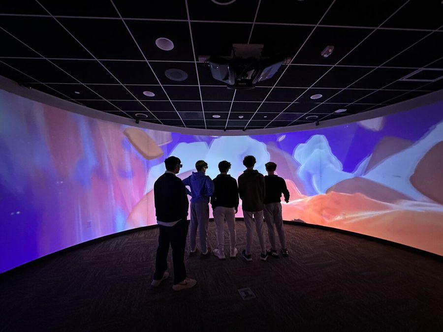 Students silhouetted against the 270-degree immersive CAVERN screen